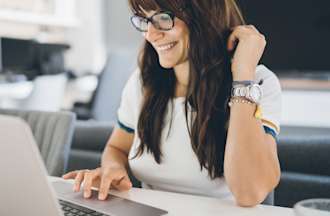 [Featured Image] A woman searches on her laptop at home for cybersecurity jobs that are in demand. 