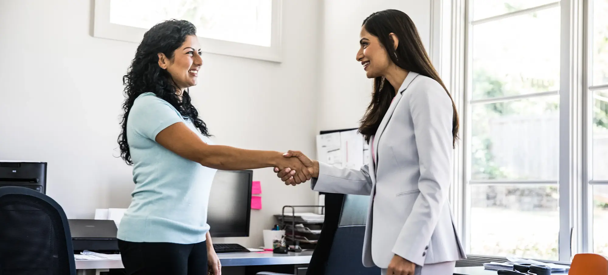 [Featured Image] An applicant shakes the interviewer's hand with confidence after practising social media manager interview questions and answers beforehand.
