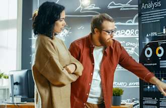 [Featured Image] Two people looking at graphs of statistic in a lab