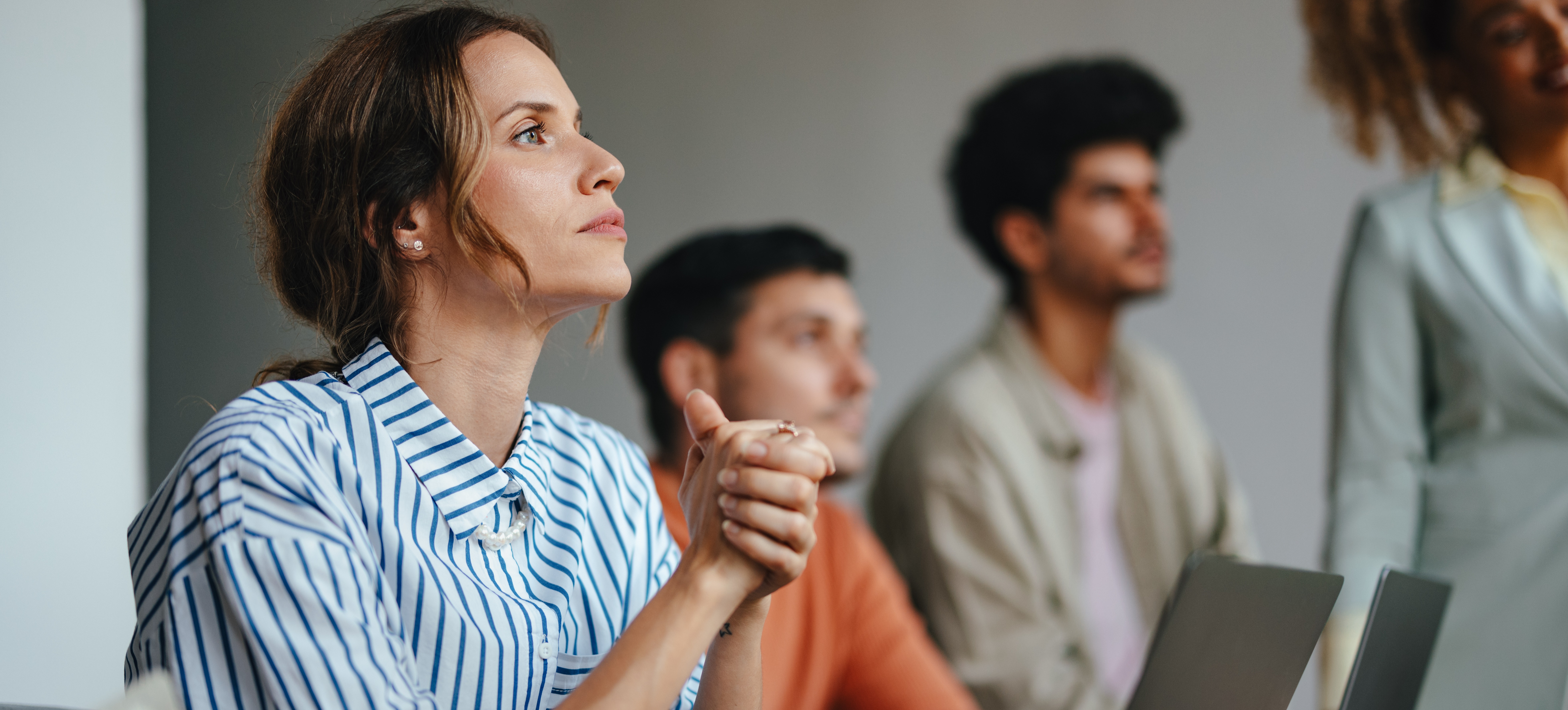 [Hauptbild] Fachleute lernen am Arbeitsplatz, indem sie an ihren Laptops sitzen und einem Referenten zuhören.