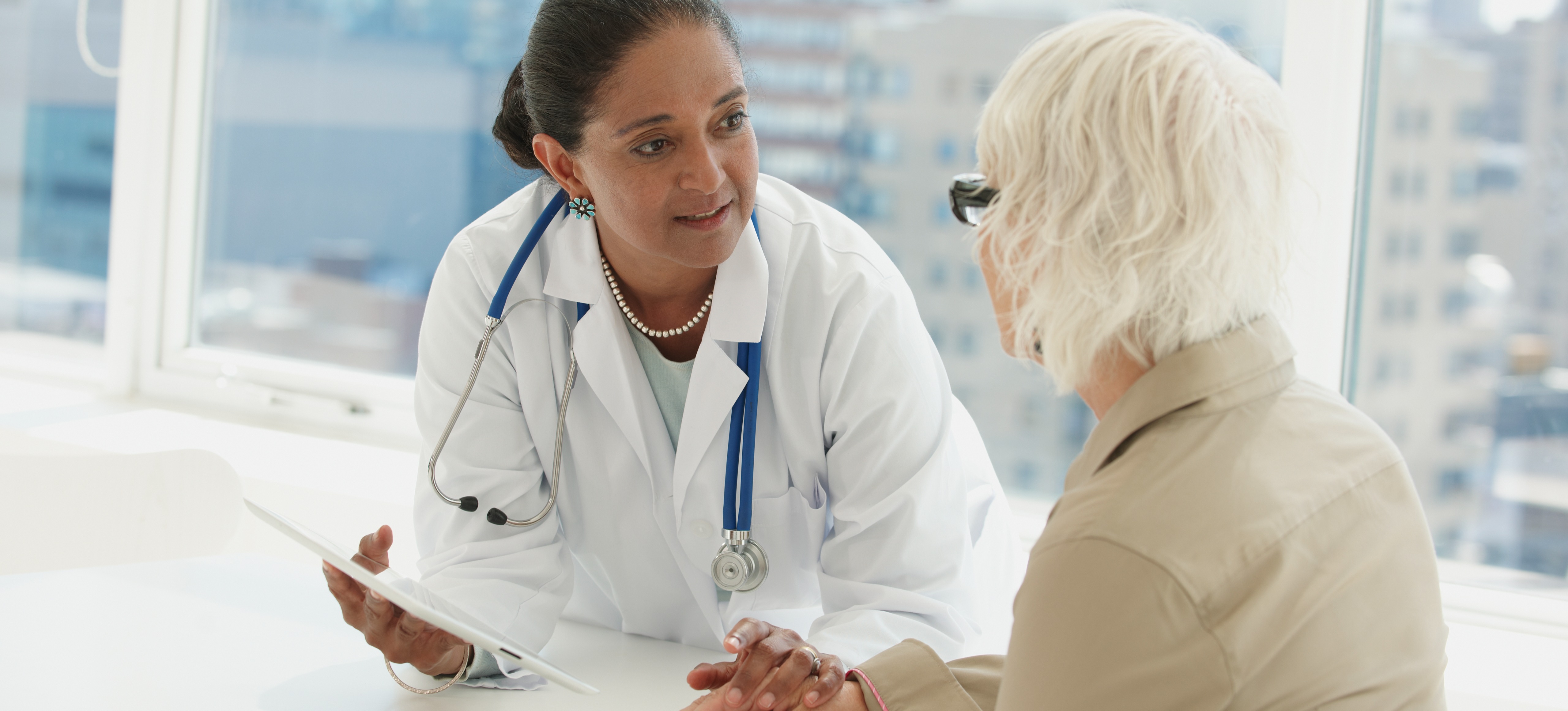 [Featured Image] A doctor working one of many jobs in the medical field touches the hand of a patient whilst discussing their medical condition. 
