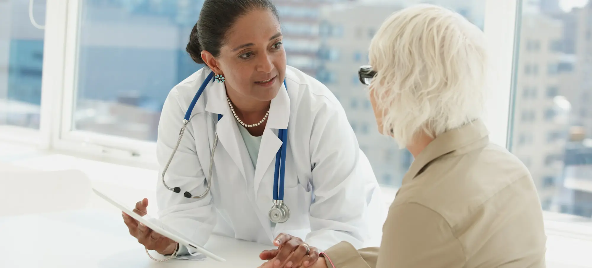 [Featured Image] A doctor working one of many jobs in the medical field touches the hand of a patient whilst discussing their medical condition. 