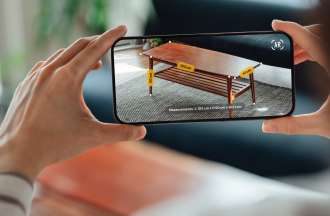 [Featured Image] A woman uses her smartphone to shop online for furniture and see how it would look in her house, one of many augmented reality examples. 