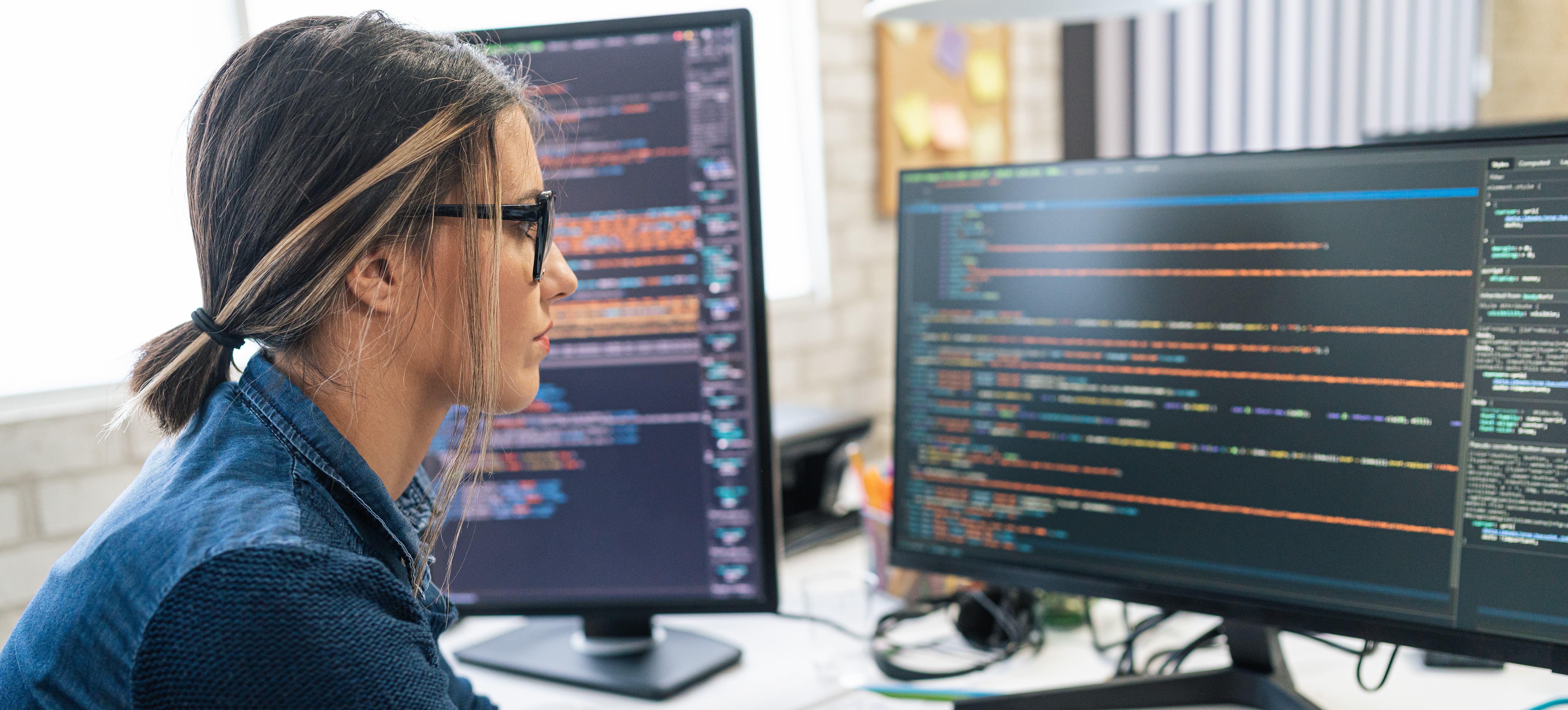 [Featured Image] A person working at a computer with two monitors improving the data governance framework for their company.