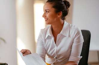 [Featured Image] A recent college graduate sits at a computer and prepares her resume to enter the tech job market as a data analyst.  
