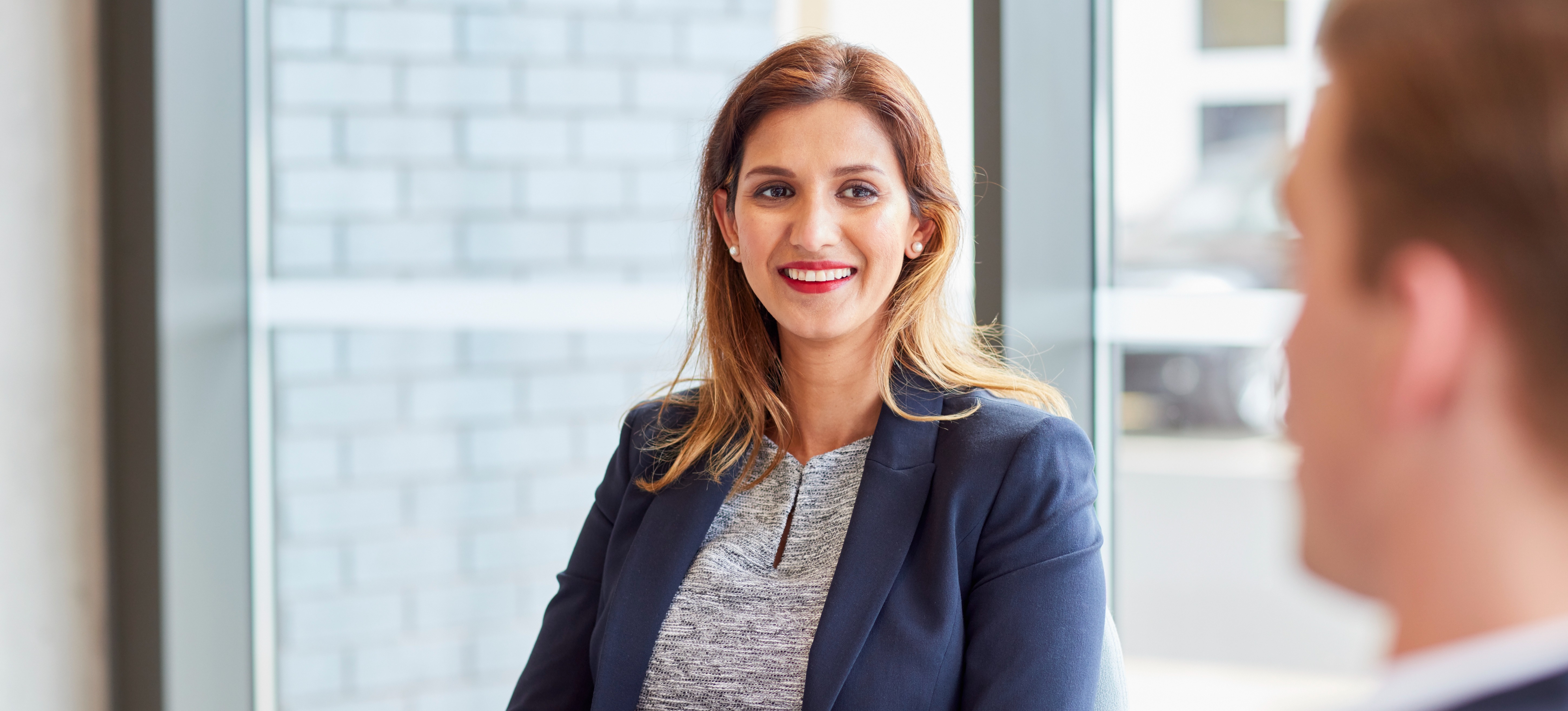 [Featured image] A person talks to a colleague about their cybersecurity jobs in government.  