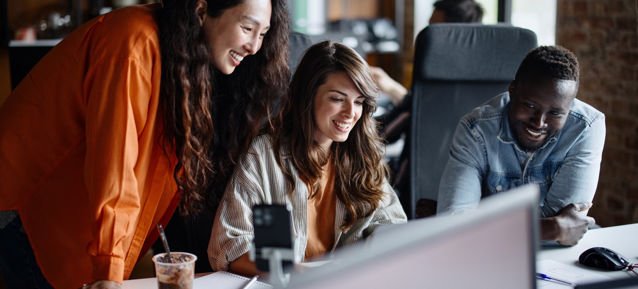 [Featured Image] A group of UX designers works on a project at a work desk and computer using design thinking frameworks.
