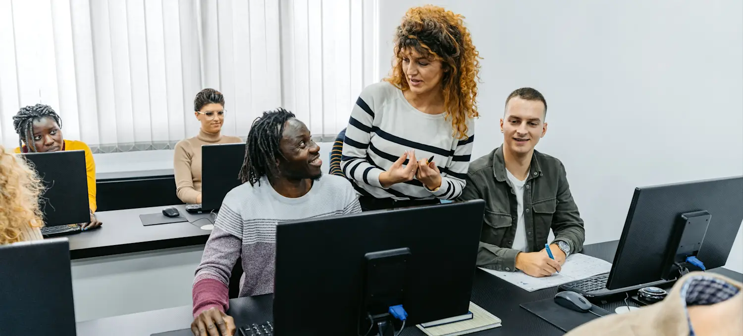 [Featured Image] A professional guides learners in a technology-equipped classroom as they help prepare them for learning and development certification.
