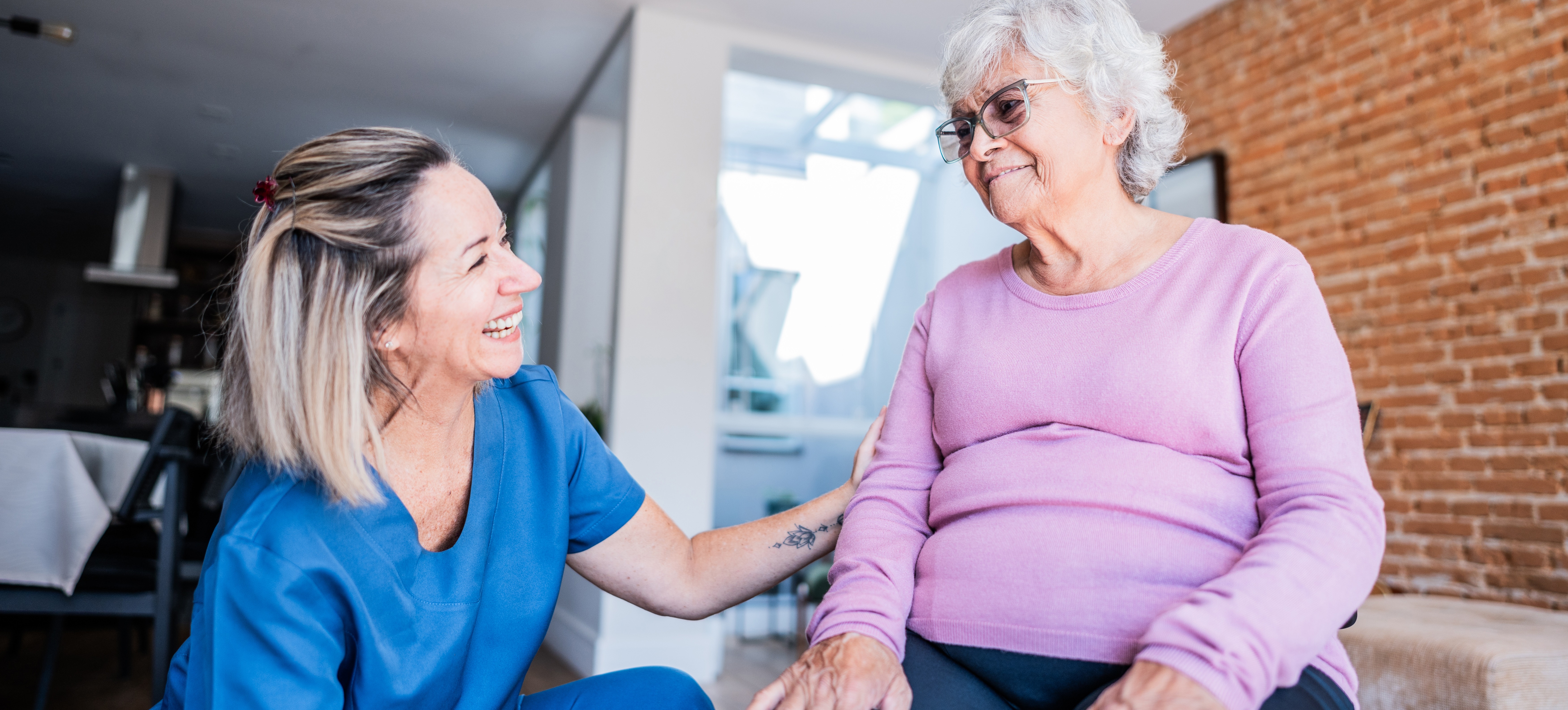 [FEATURED IMAGE] An occupational therapist assistant in blue scrubs works alongside a patient.
