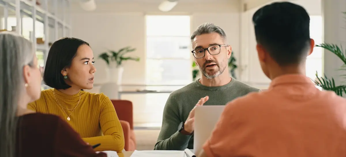 [Featured Image] A business intelligence analyst meets with a small team of colleagues to discuss data insights.
