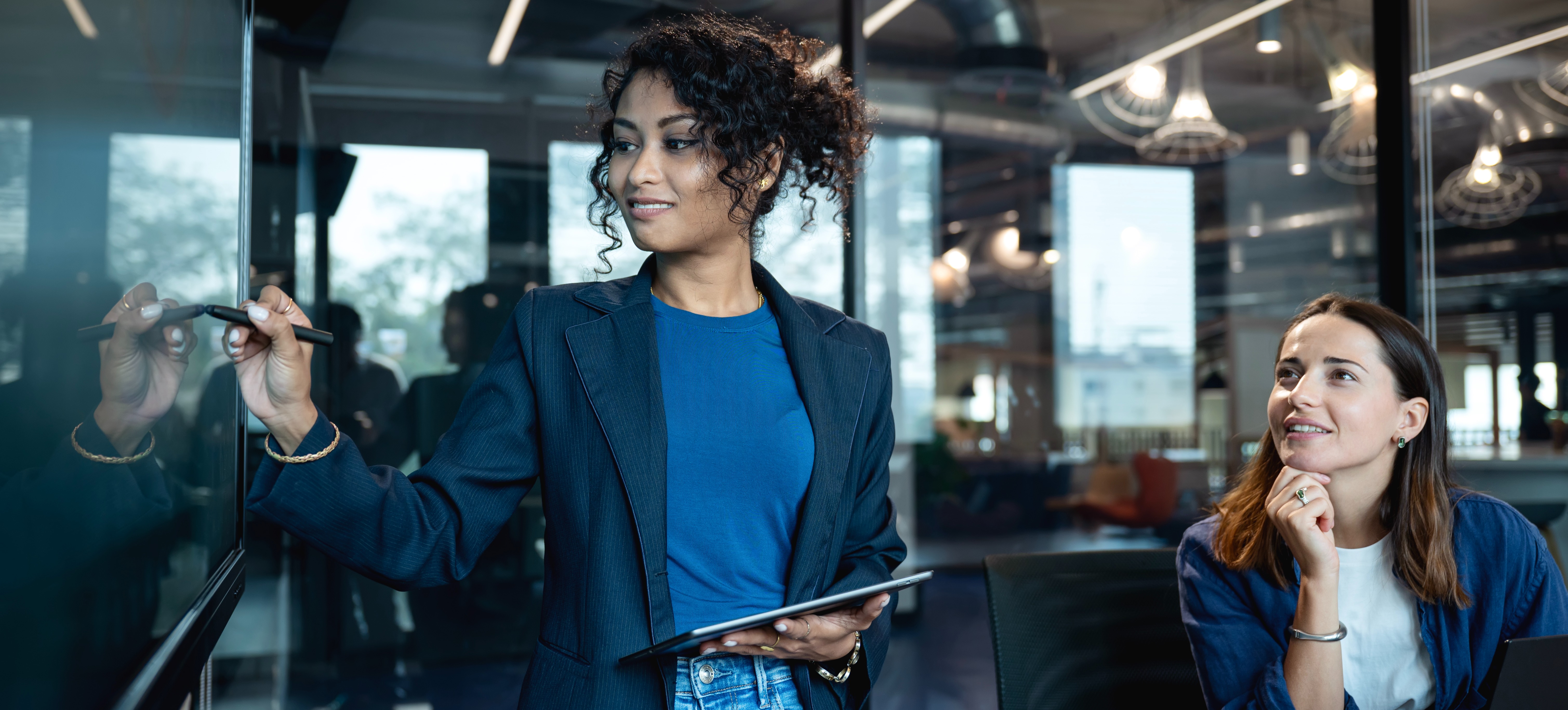 [Featured Image] Female employer uses digital display to show employees what data structures are and how they can be useful