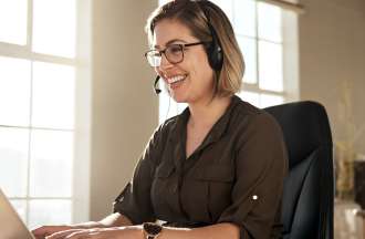 [Featured Image] A UX data analyst wears a headset, sits at a desk in her office, and uses a computer to look at data to determine whether her organization's product is user-friendly. 
