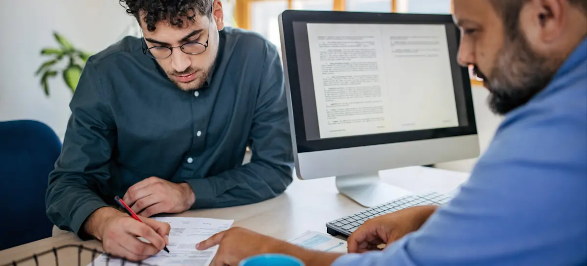 [Featured image] A possible future coworker discusses his resume with a hiring manager.