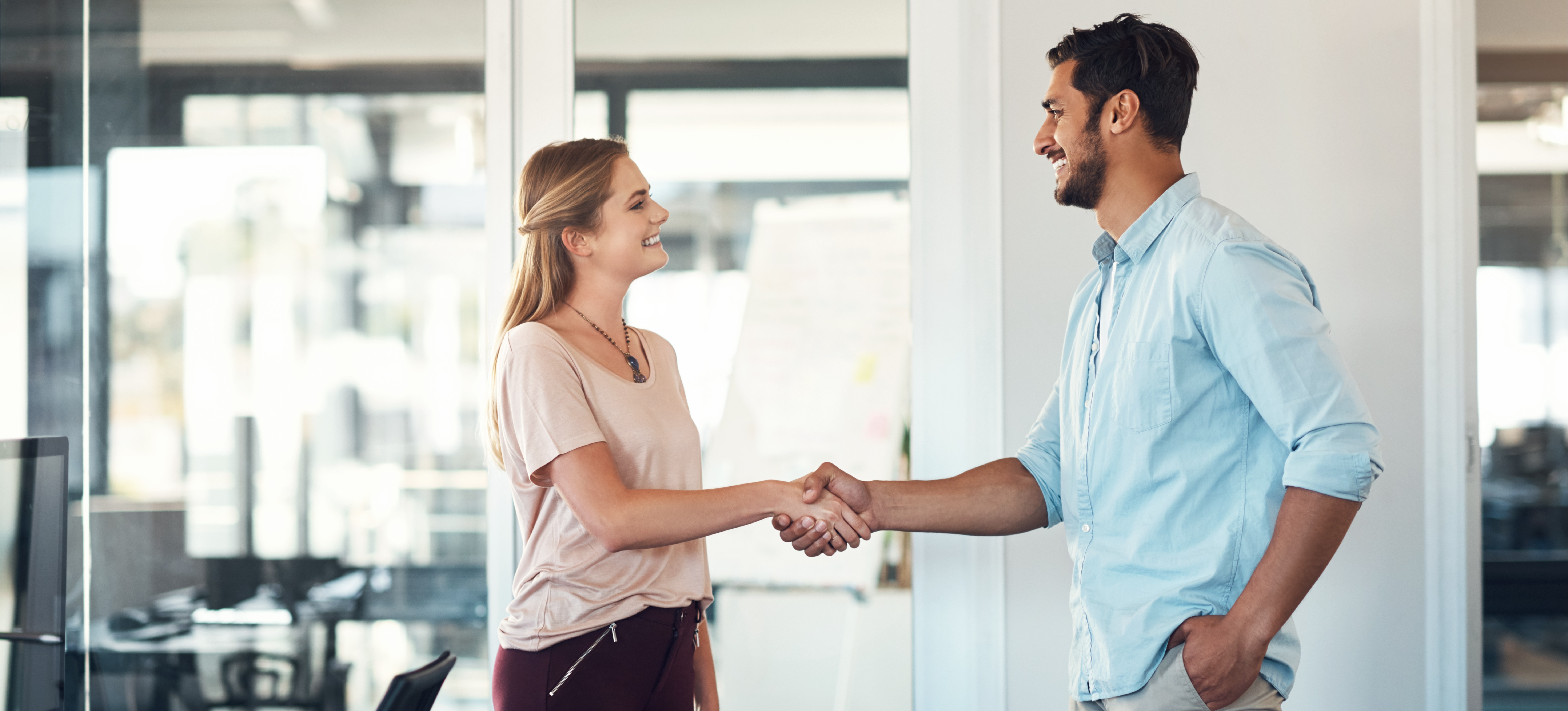 [Featured Image] Two people shake hands in an office while discussing how many hours is part time after a job interview.