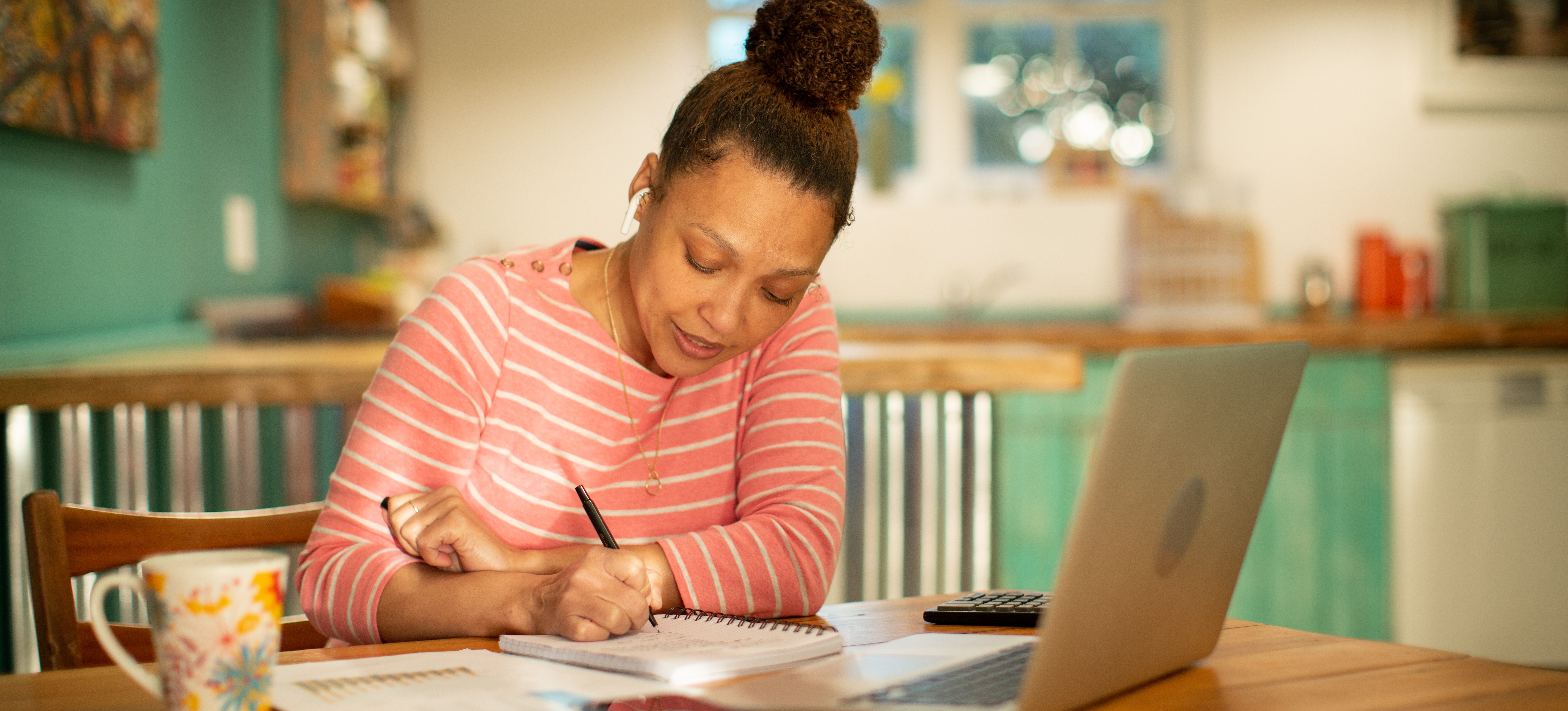 [Featured Image] A person sits at a table with a laptop, notebook, and study materials, studying for an online accounting degree.
