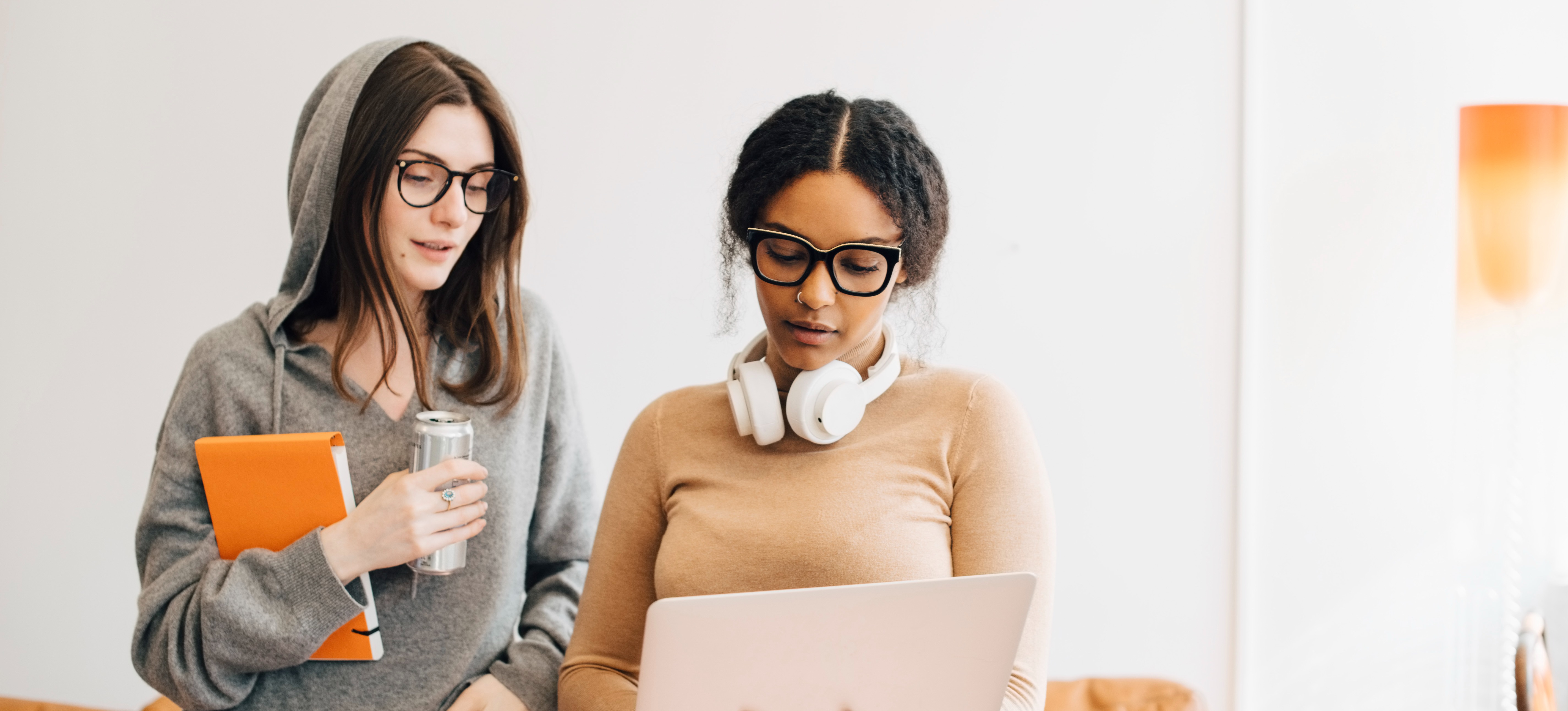 [Feature Image] Two friends standing in a brightly lit room discuss how to use Google Gemini.
