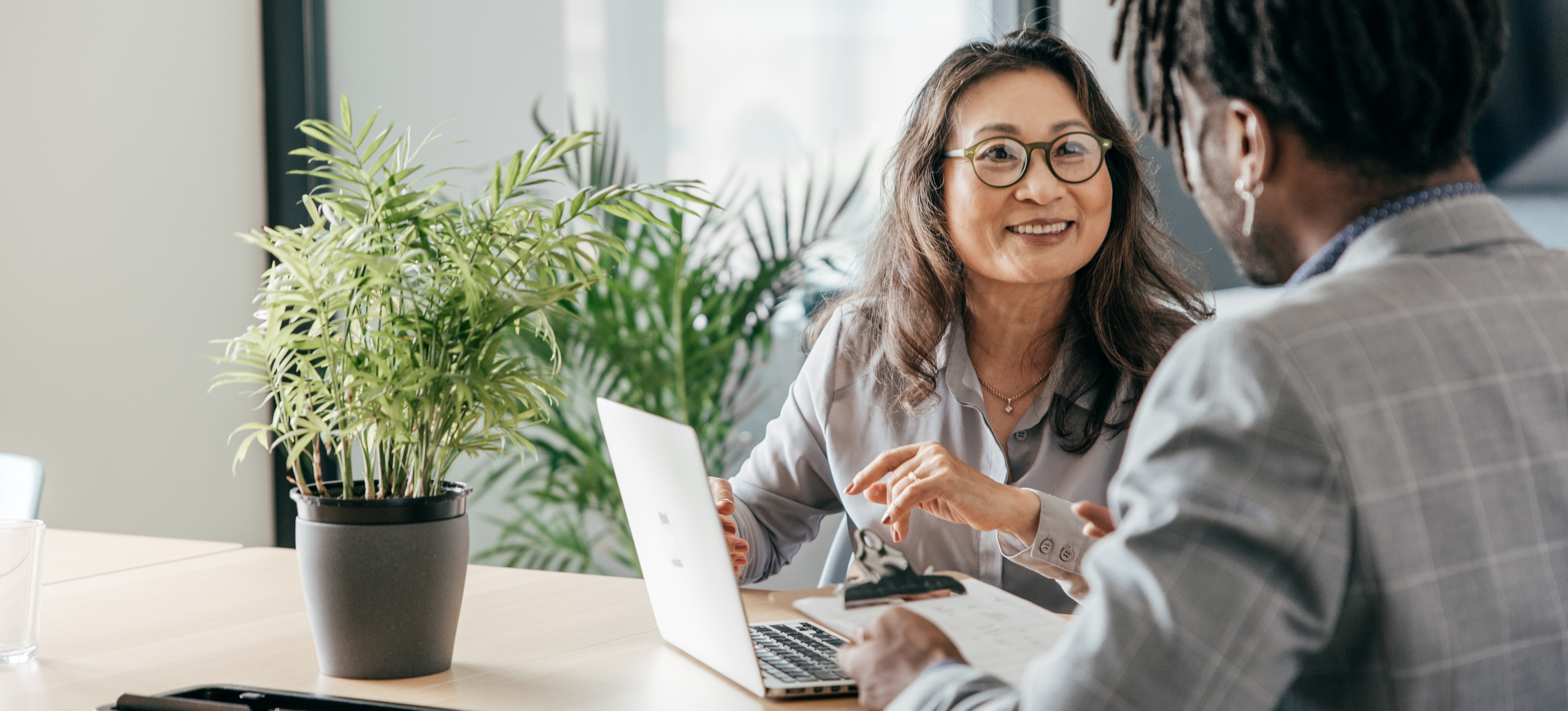 [Featured image] A manager coaches their employee while sitting at a conference table with a laptop.