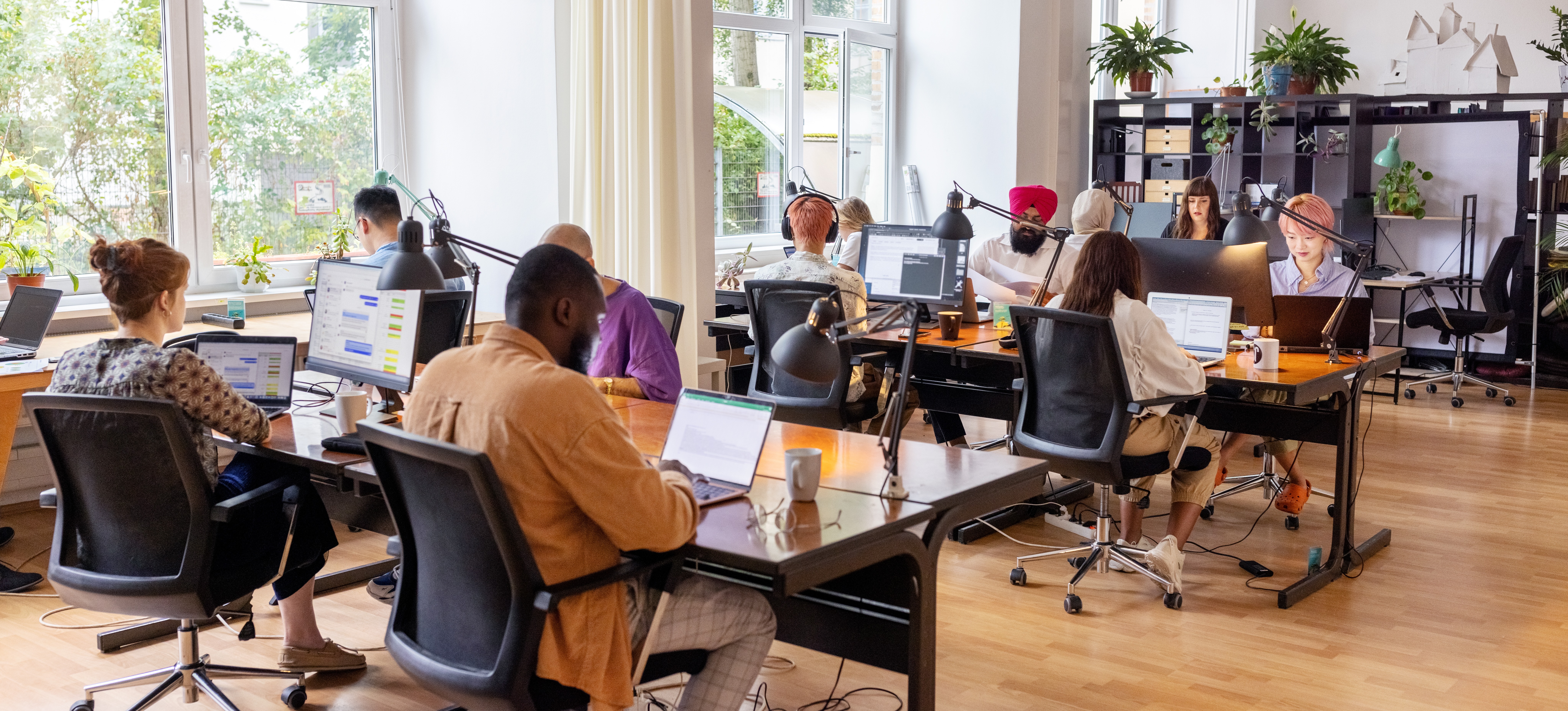 [Featured Image] A large team of web developers work on new project in local office space