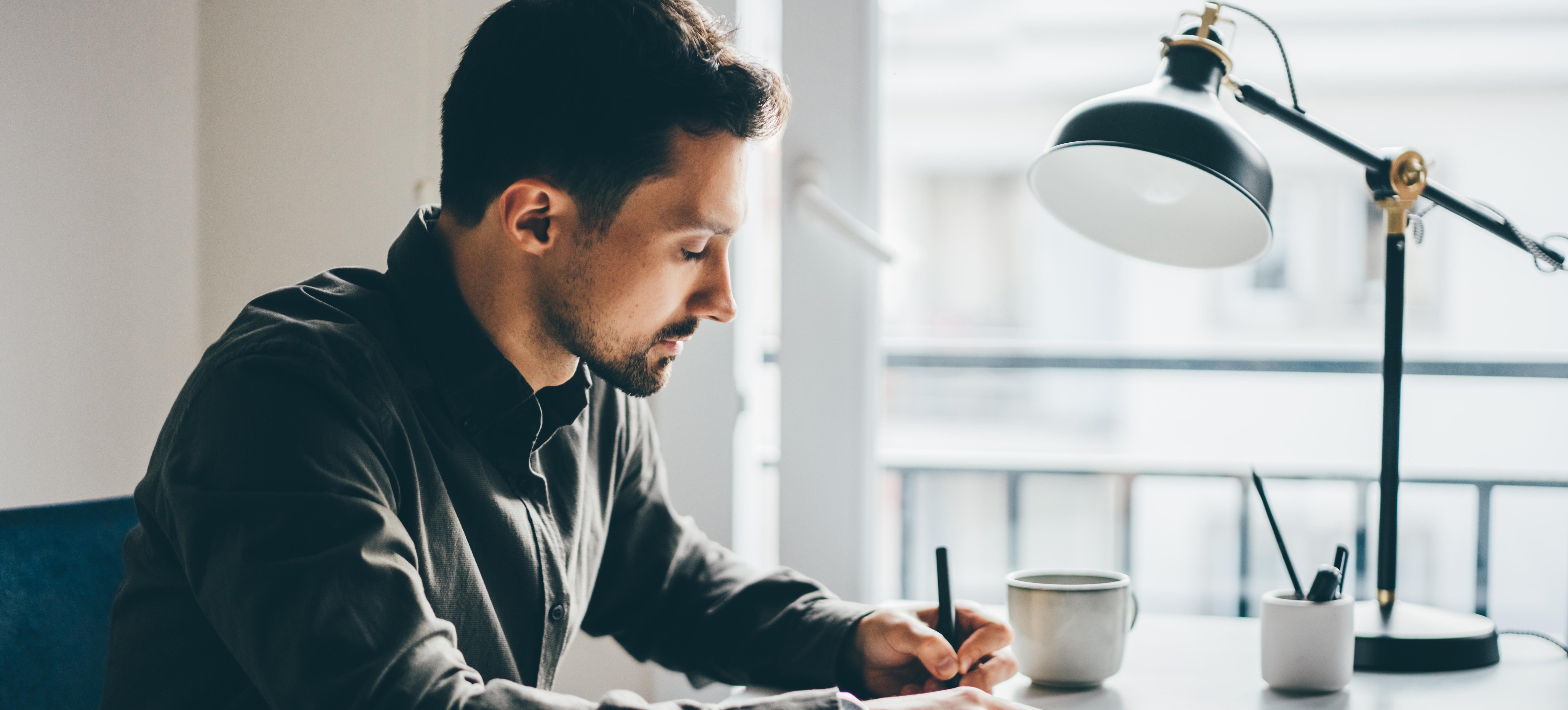 [Featured Image]: A man sitting at a desk with a notebook demonstrates how to write a white paper.
