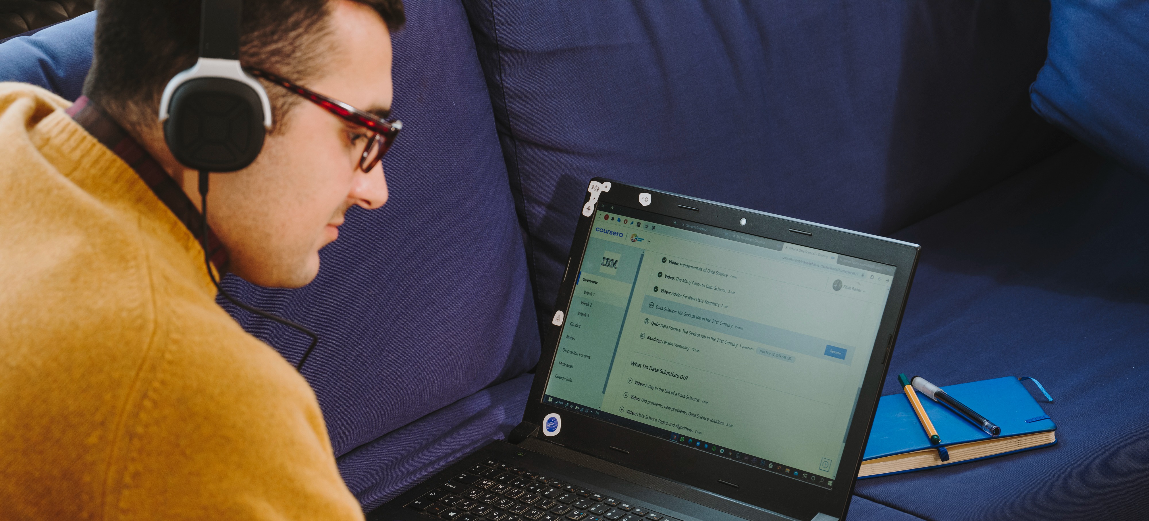 [Featured Image]:  A data engineer, sitting at this desk and working on his laptop computer, as he works to get a data engineer certification.
