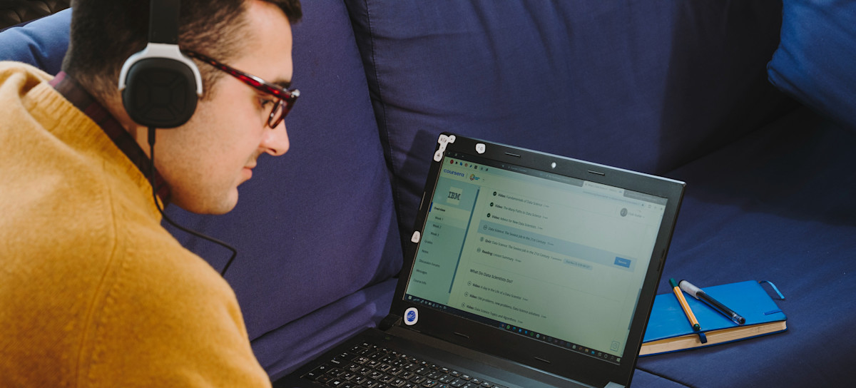 [Featured Image]:  A data engineer, sitting at this desk and working on his laptop computer, as he works to get a data engineer certification.