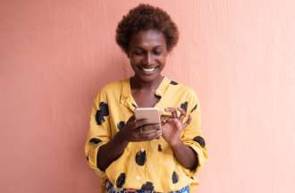 [Featured Image] A woman stands outside using a smart phone.