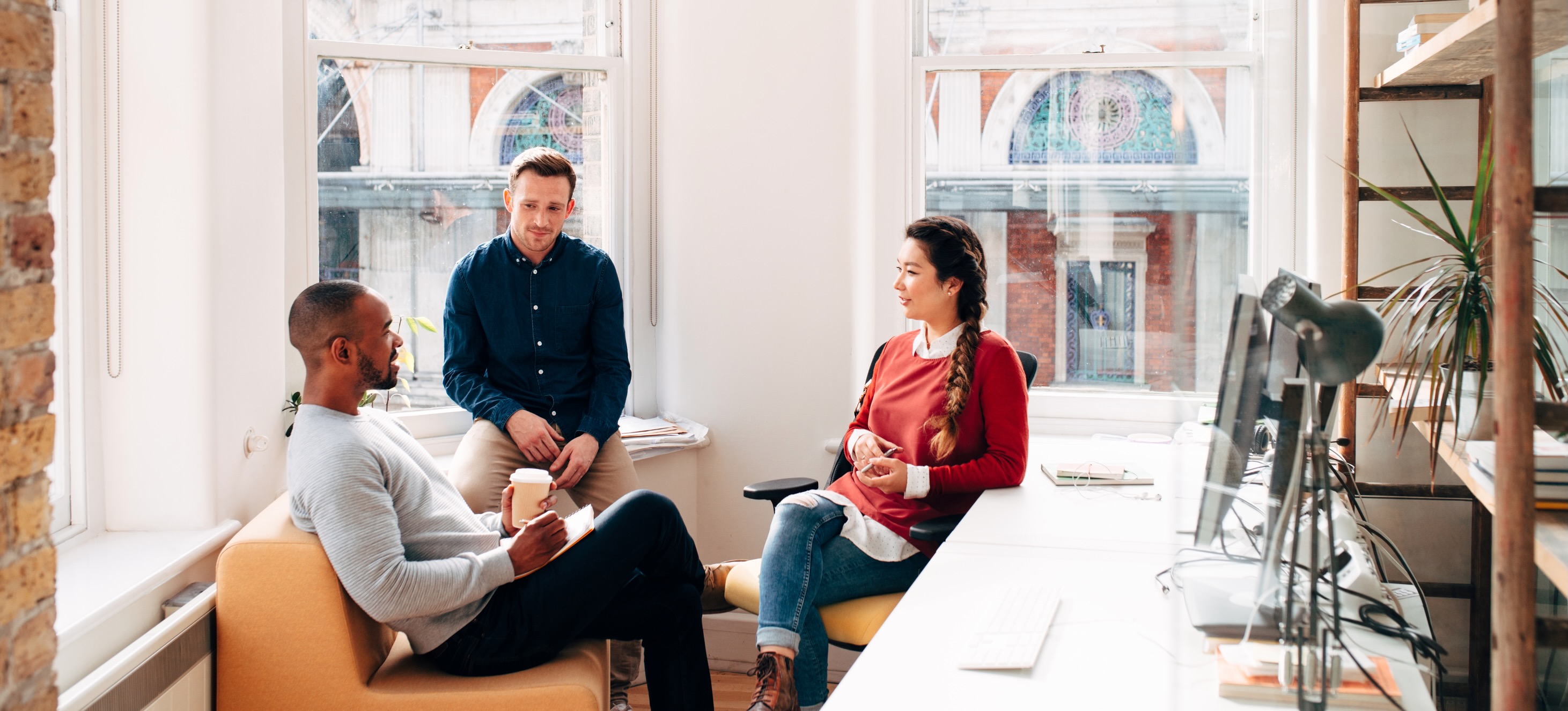 [Featured Image] A group of coworkers in an office discuss the concept of growth mindset and how it contributes to their work everyday. 