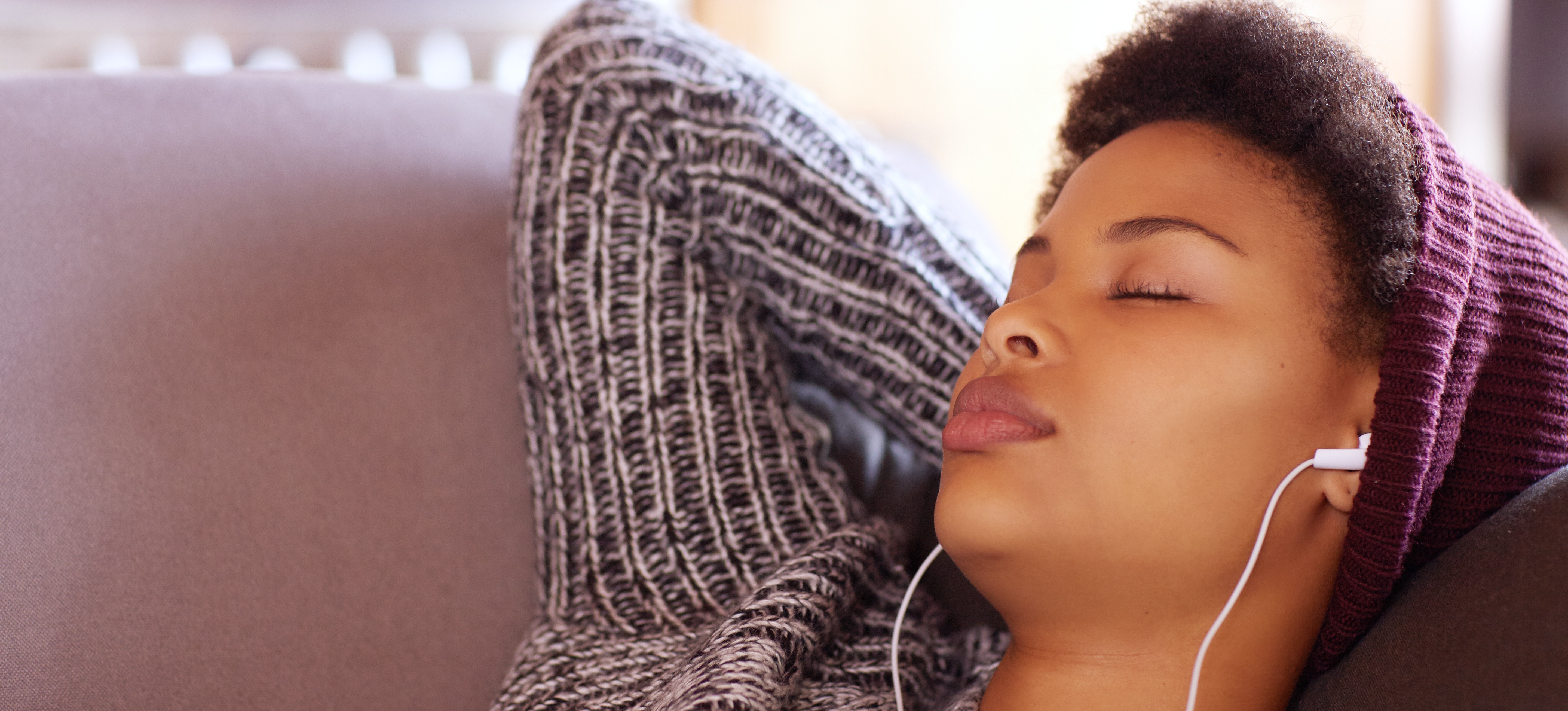 [Featured Image] A young woman sleeps while listening to music through earbuds in an effort to learn while sleeping.