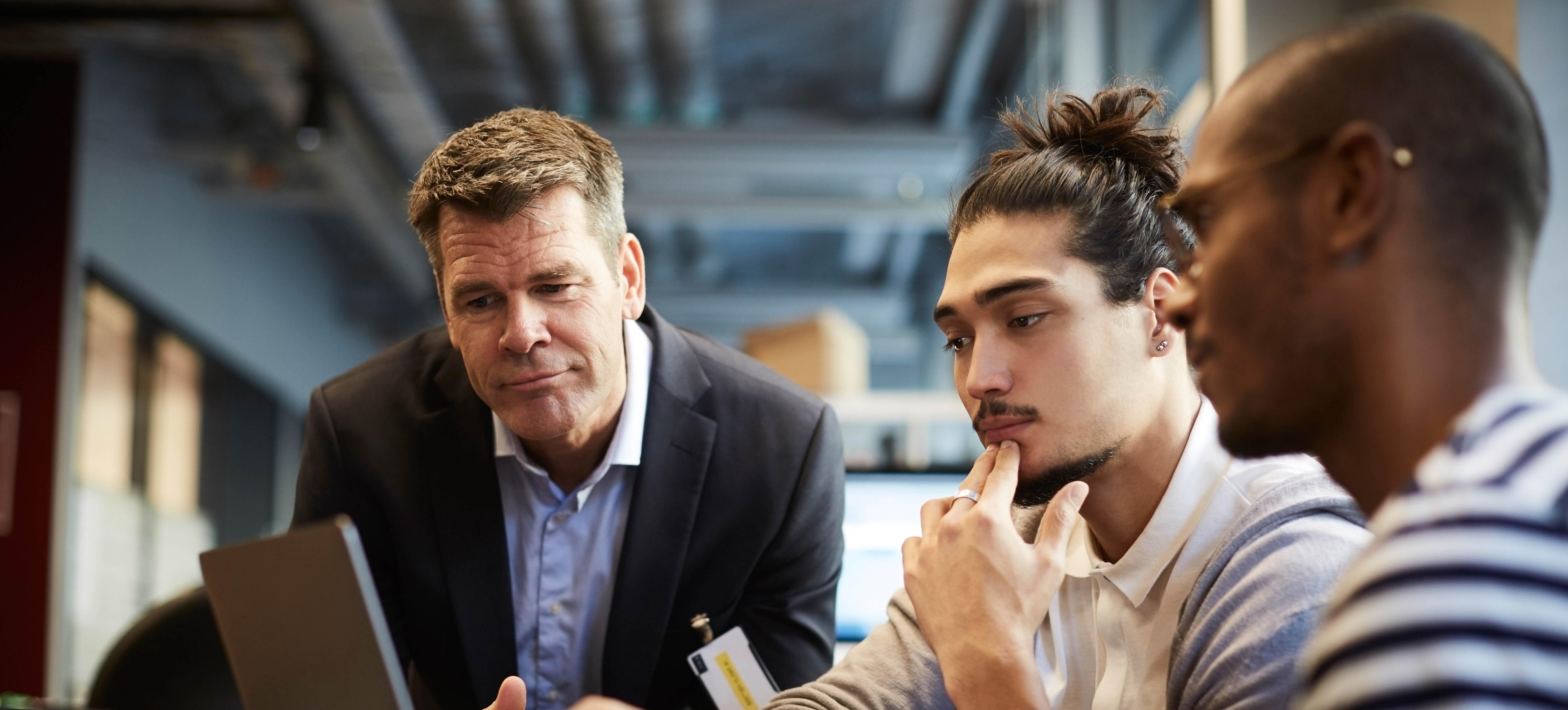 [Featured Image] Three professionals in the banking industry use machine learning for fraud detection as they look at a computer screen.
