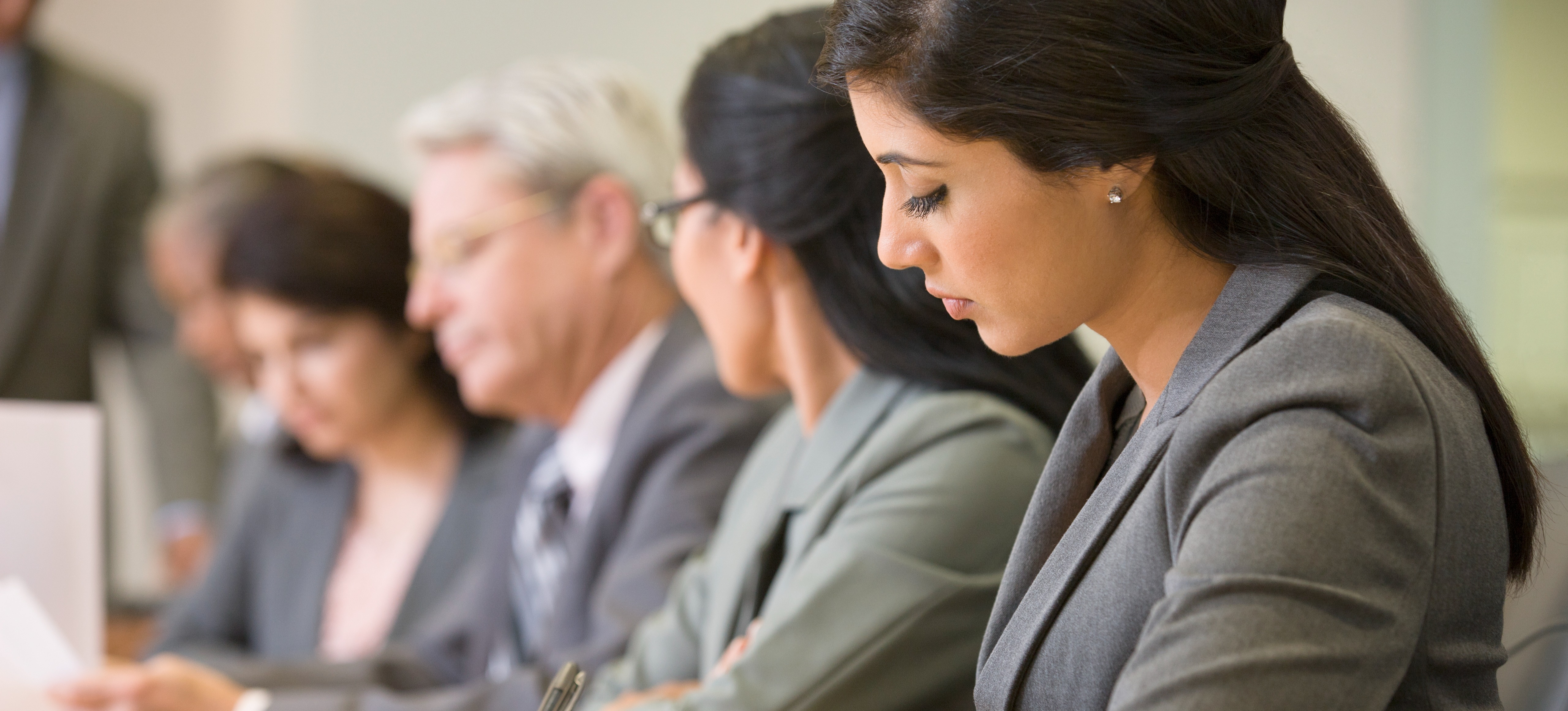 [Featured Image] A group of employees meets in a conference room with smartphones and notebooks to go over information from their cybersecurity jobs in Maryland. 
