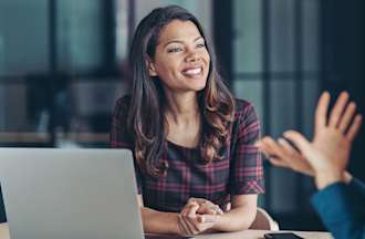 [Featured Image] Two women have a conversation in an office conference room. 