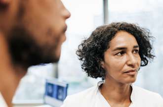 [Featured image] A certified medical assistant in a white lap coat looks at lab results with a physician.