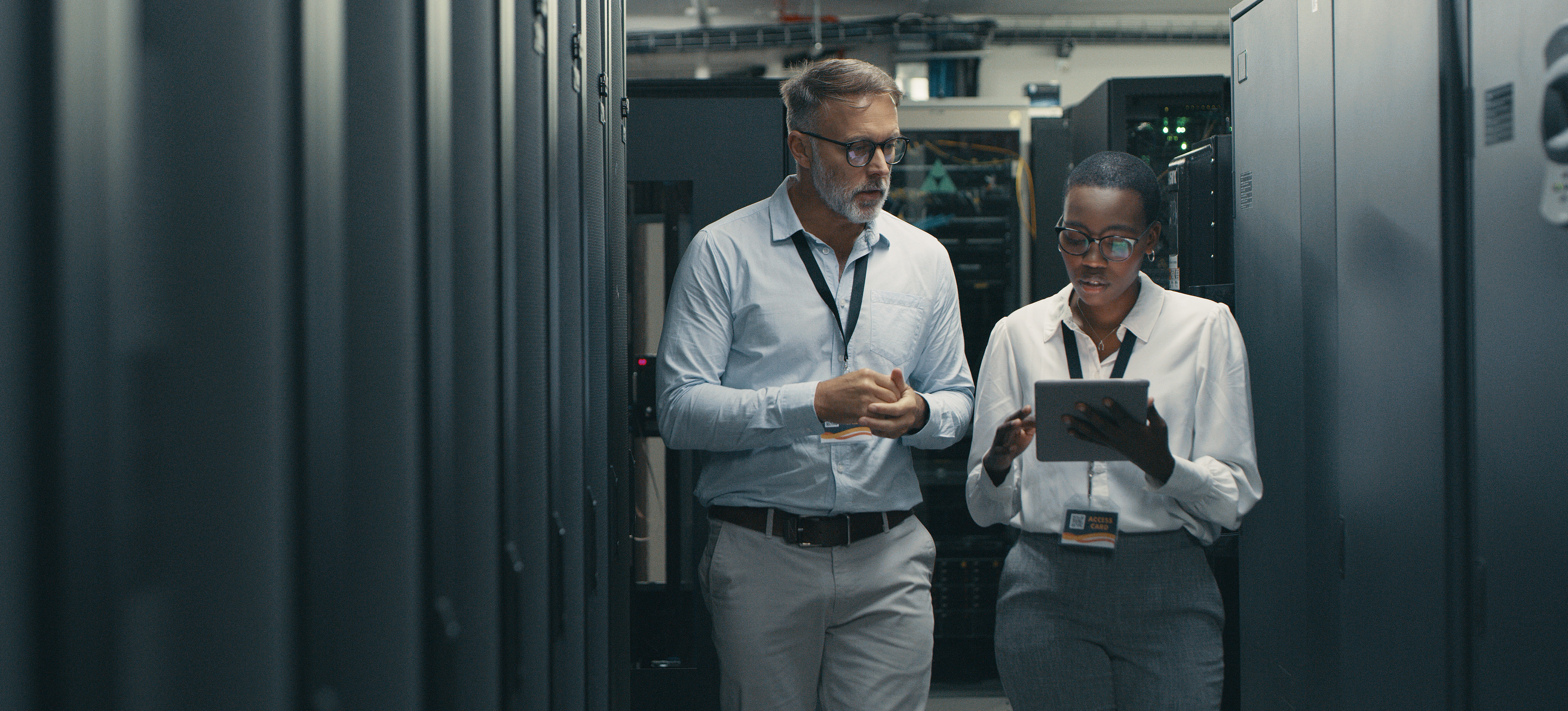 [Featured Image] Two cybersecurity experts working in a data center discuss various types of firewalls.
