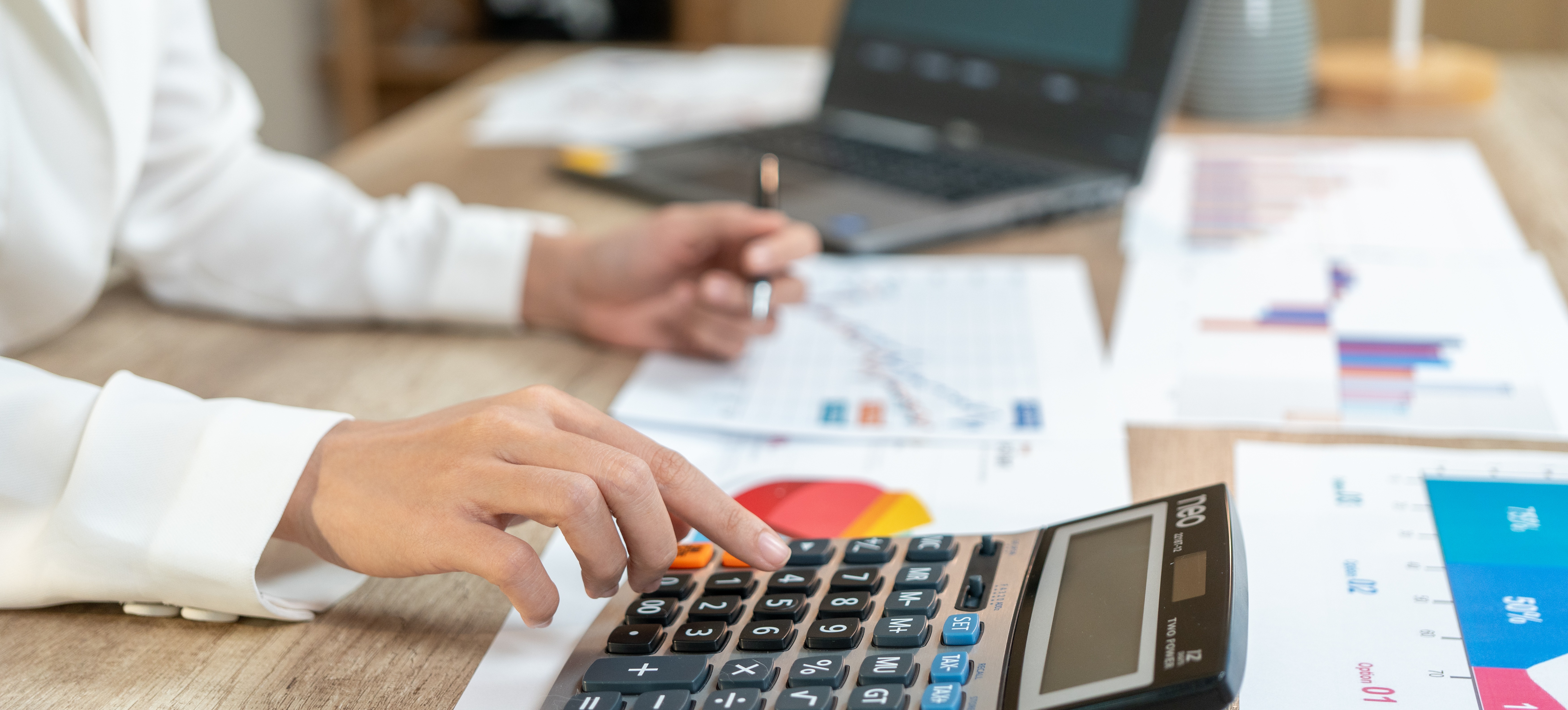 [Featured Image] An accountant is at thier desk crunching numbers with a calculator, confirming the reports AI-generated.
