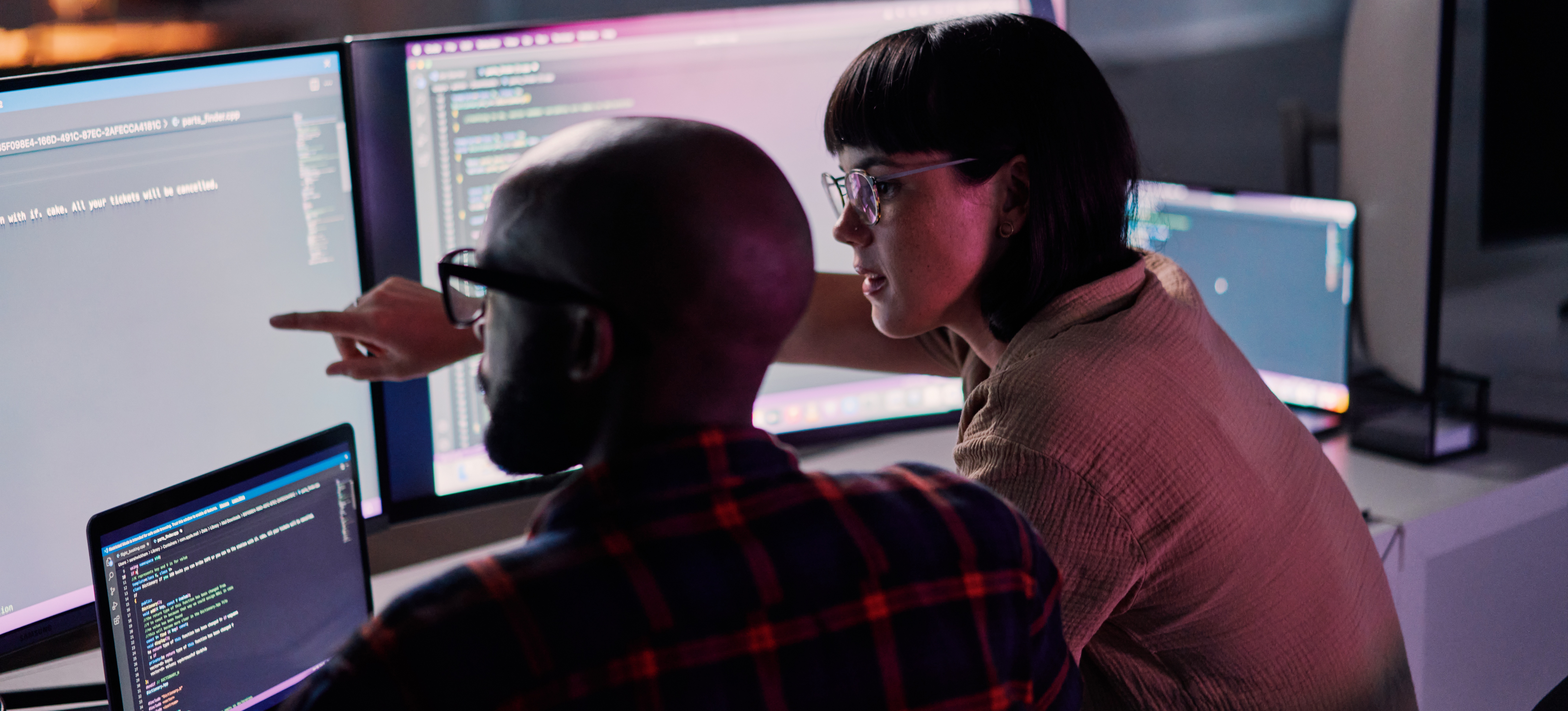 [Featured Image]: Professionals in a work environment interacting about an AI governance job while working on computers with code.
