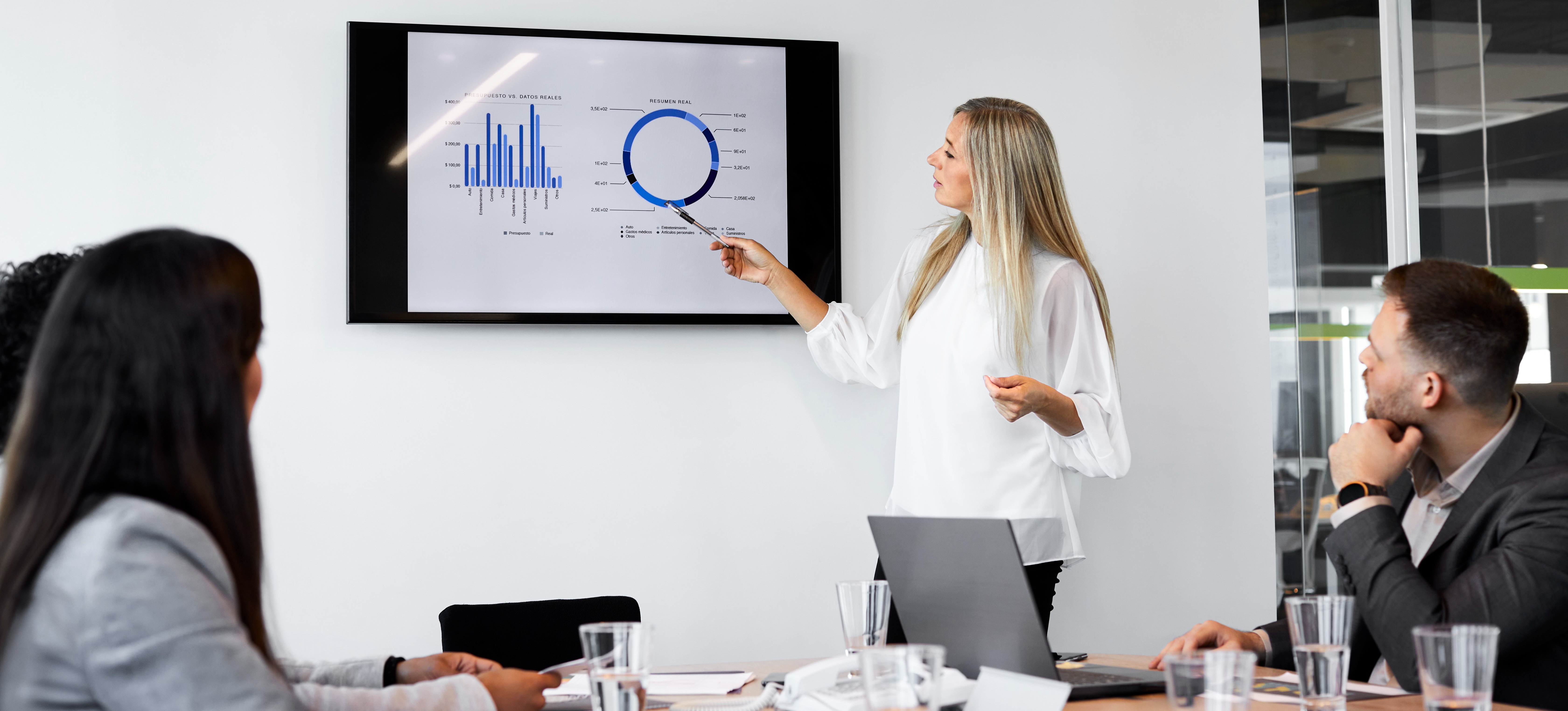 [Featured Image] A woman working on a data science manager salary presents data on a screen to her colleagues in a business meeting setting.
