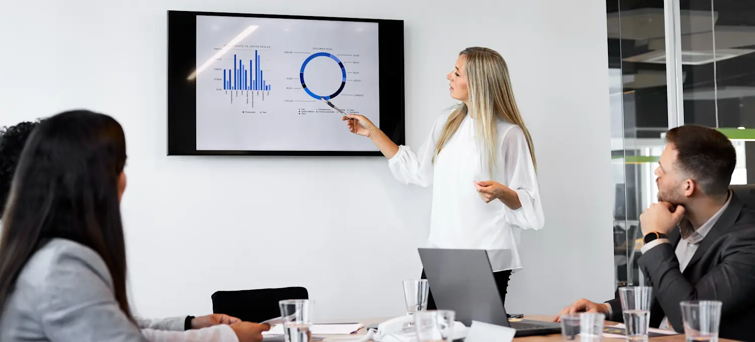 [Featured Image] A person working on a data science manager salary presents data on a screen to their colleagues in a business meeting setting.

