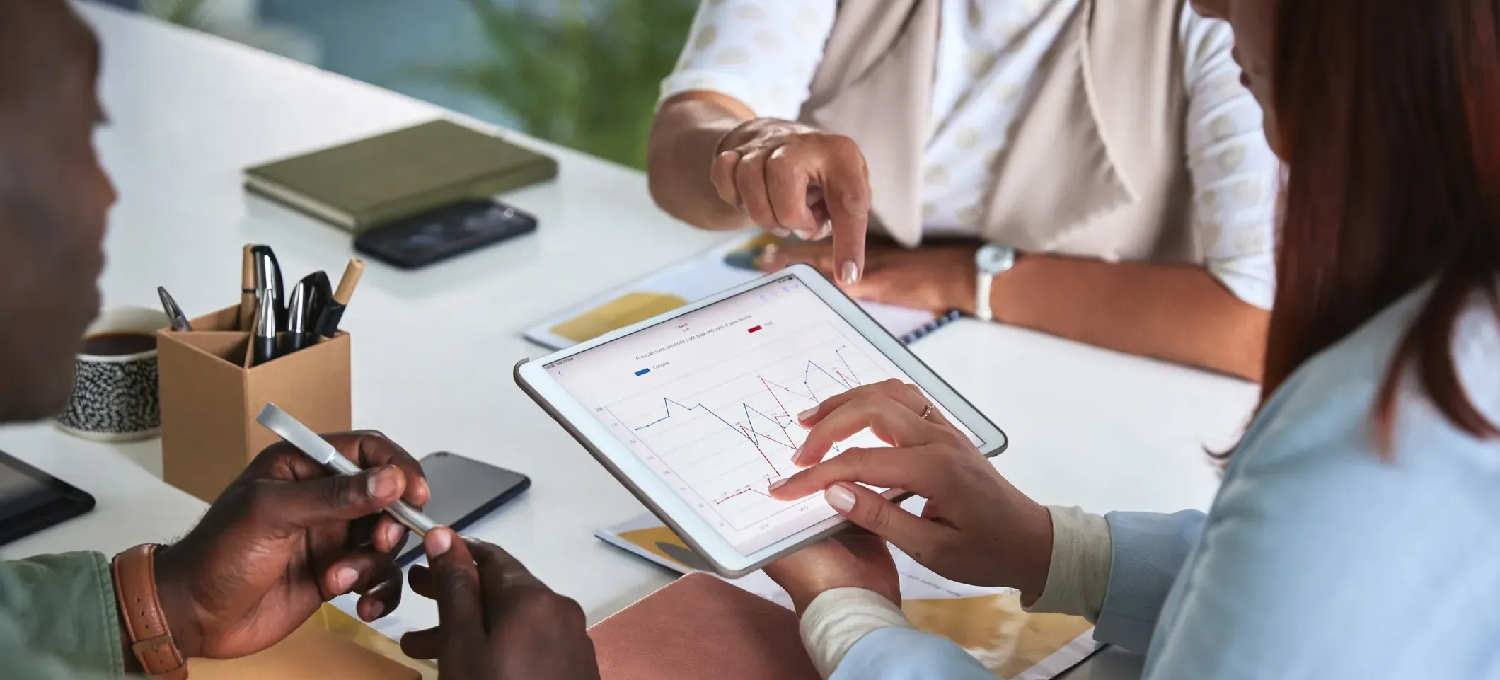 [Featured Image]: Three people sitting at a table look at a tablet showing data that reflects a Gaussian distribution.
