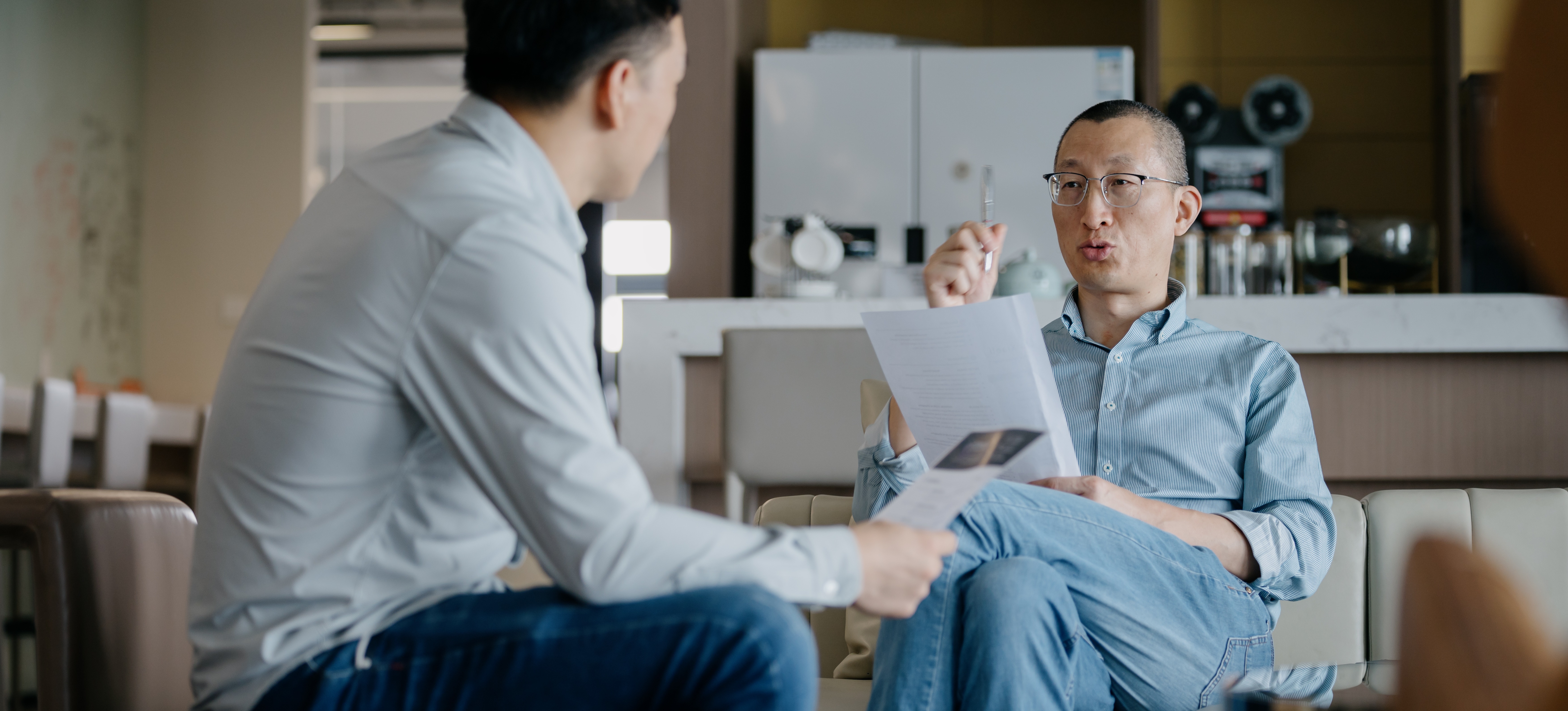 [Featured Image] A businessperson in a comfortable break room asks ChatGPT interview questions to a potential new hire.