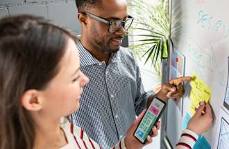 [Featured Image] A man and woman map out a mobile app design on a whiteboard.