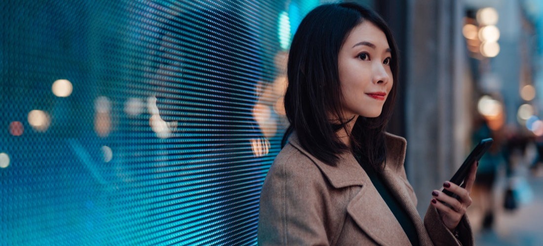 [Featured image] Person holds a smartphone and listens as Google video ads play.