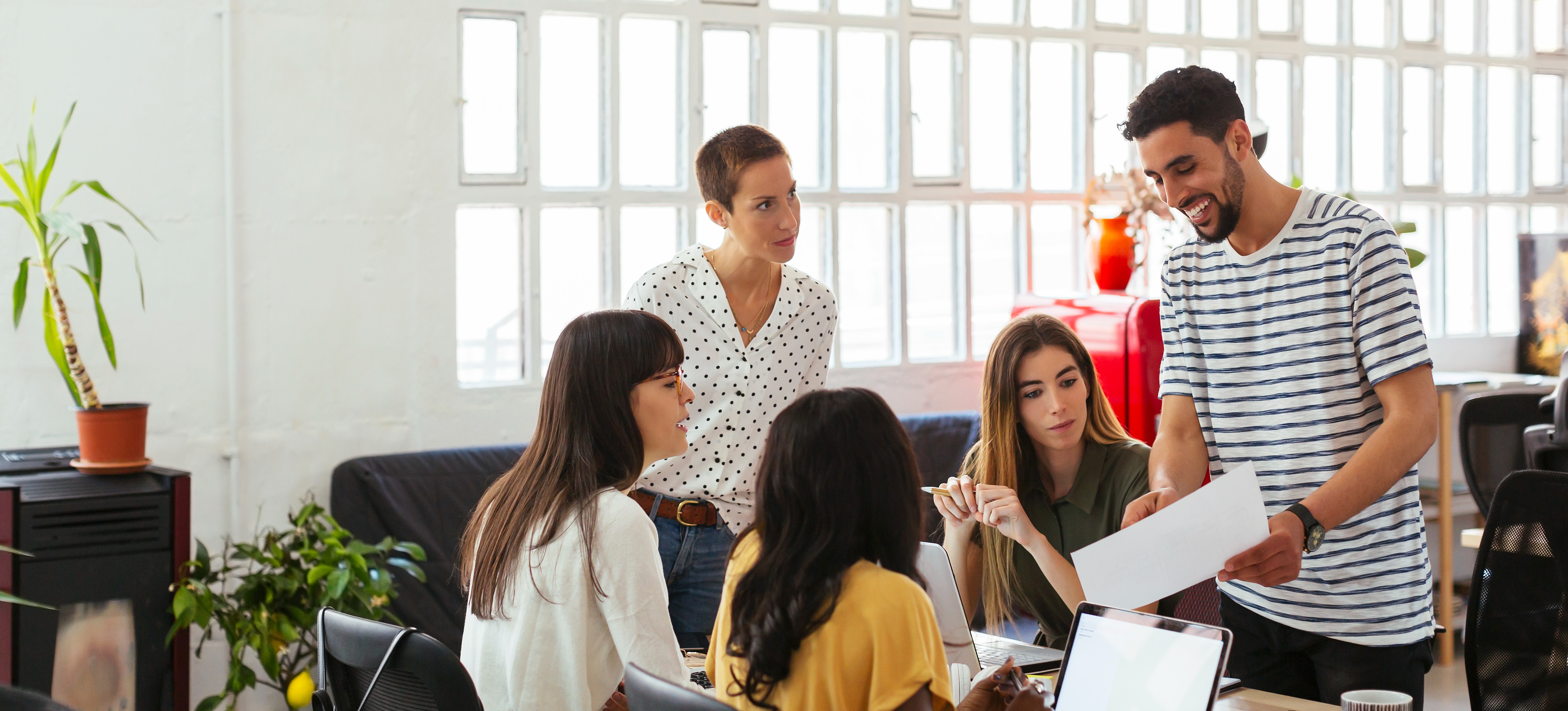 [Featured Image] A group of machine learning engineers gather around a desk to talk about regularization in machine learning. 