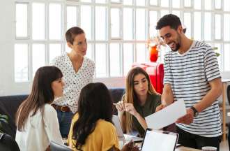 [Featured Image] A group of machine learning engineers gather around a desk to talk about regularization. 