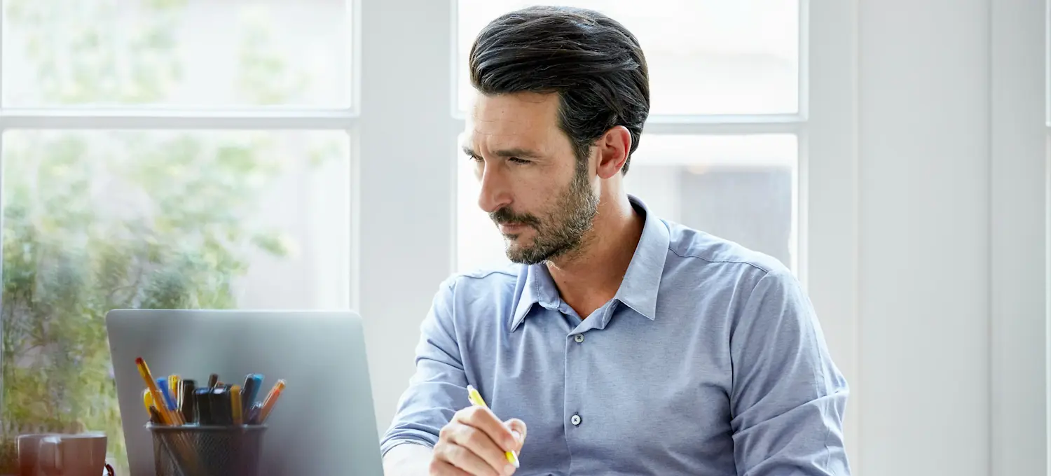 [Featured Image] A person sitting in their office with their laptop researching "What is cloud native?".
