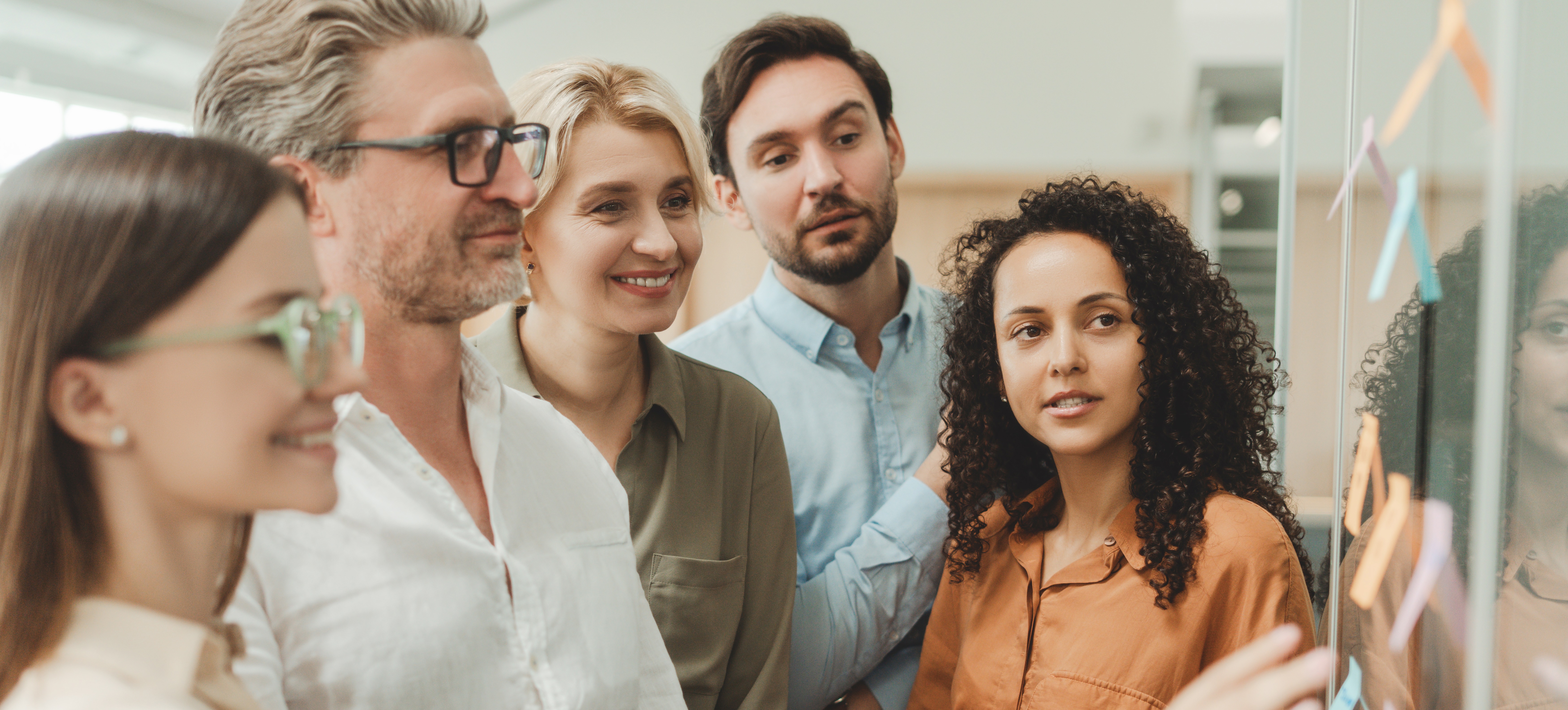 [Featured Image] A group gathers around a board with sticky notes as they study principles they need to master to become a Certified Scrum Product Owner (CSPO).
