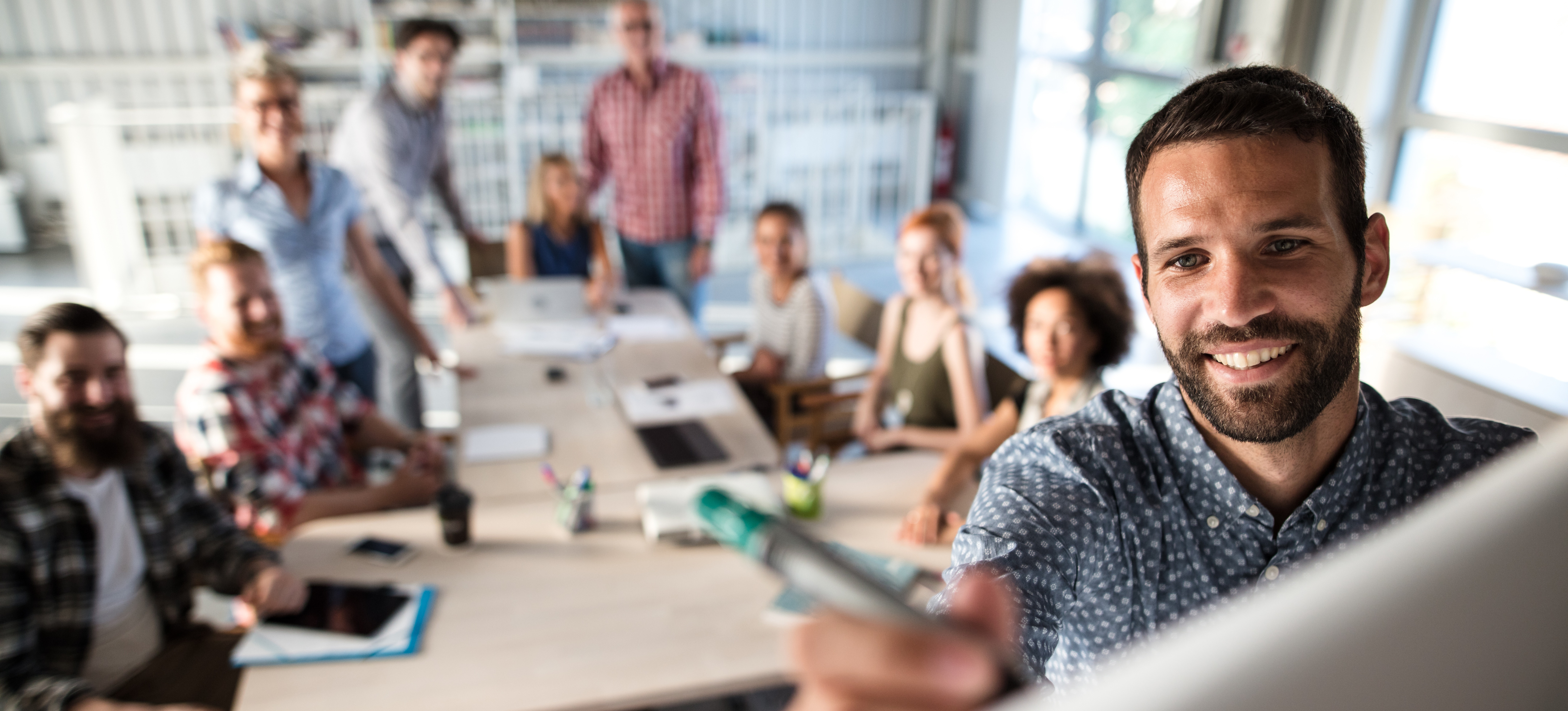 [Featured Image] A man writes on a whiteboard in a room filled with professionals attending a course to learn SQL.
