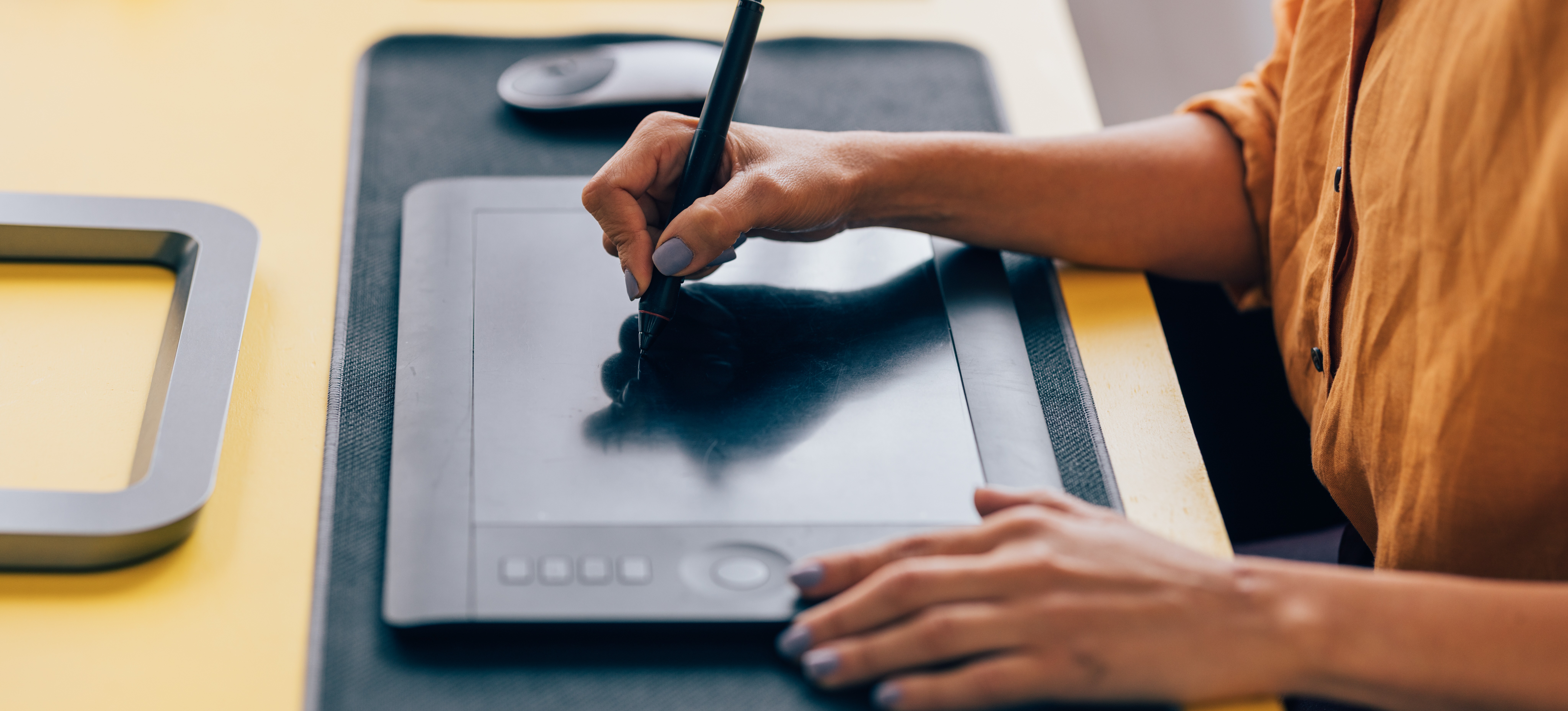 [Feature Image] A female graphic designer uses a tablet to design a custom NFT for a client
