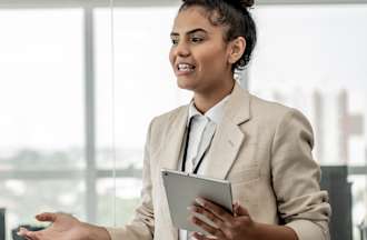 [Featured image] A data protection officer holds a tablet and talks to employees about the importance of data compliance. 