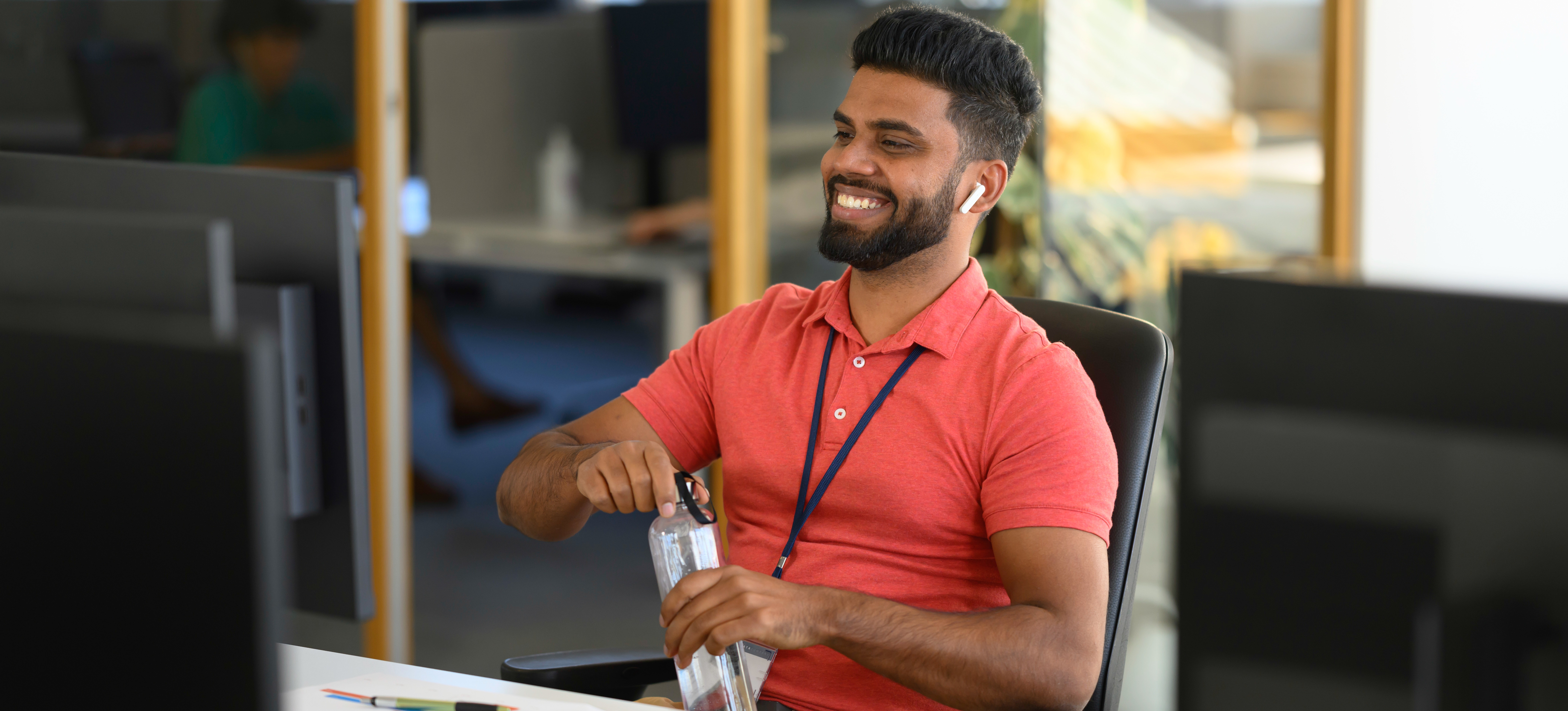 [Featured Image] Smiling marketer looks at their computer in a sunny office.