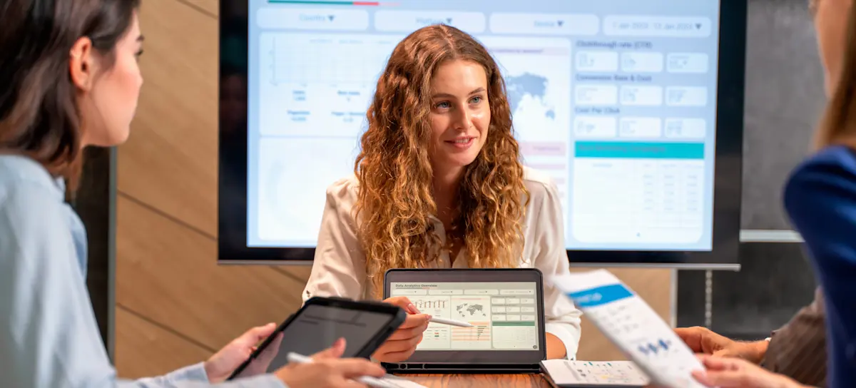 [Featured Image] Three data analysts seated at an office table, using data interpretation to inform business decisions.
